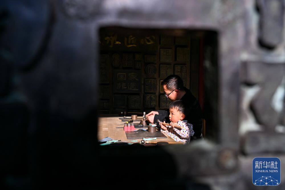 3月25日，在会泽县国家级非遗斑铜制作技艺传习馆，张氏斑铜第十三代传人张伟在教儿子敲打铜器。传习馆开设在会泽古城江西会馆内，江西会馆又称万寿宫，始建于清康熙年间。