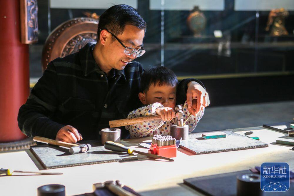 3月25日，在会泽县国家级非遗斑铜制作技艺传习馆，张氏斑铜第十三代传人张伟在教儿子敲打铜器。传习馆开设在会泽古城江西会馆内，江西会馆又称万寿宫，始建于清康熙年间。